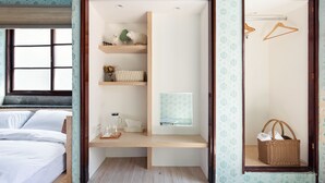 A bedroom with a bed, a wooden desk, shelves with decorative items, a mirror, and a hanging basket. - Civil Life Guesthouse Tainan (Tainan)