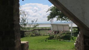 A view from a stone building with a brick pathway leading to a grassy area with a swing set and flowers. - Lei Thar Gone Guest House (Yenangyaung)