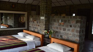 A room with two beds, a stone wall, a mirror, and a vase with flowers. - Lei Thar Gone Guest House (Yenangyaung)