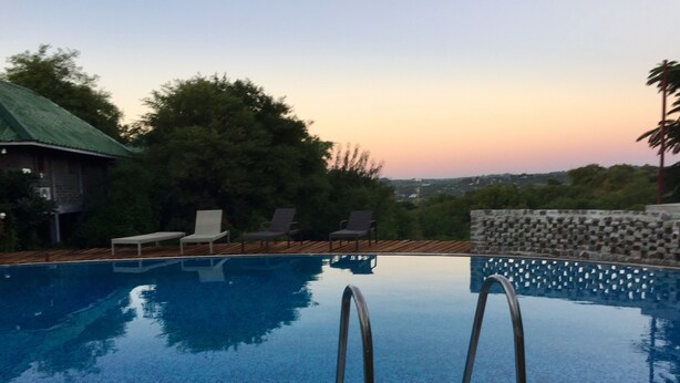 A swimming pool with a view of the sunset and surrounding greenery. - Lei Thar Gone Guest House (Yenangyaung)