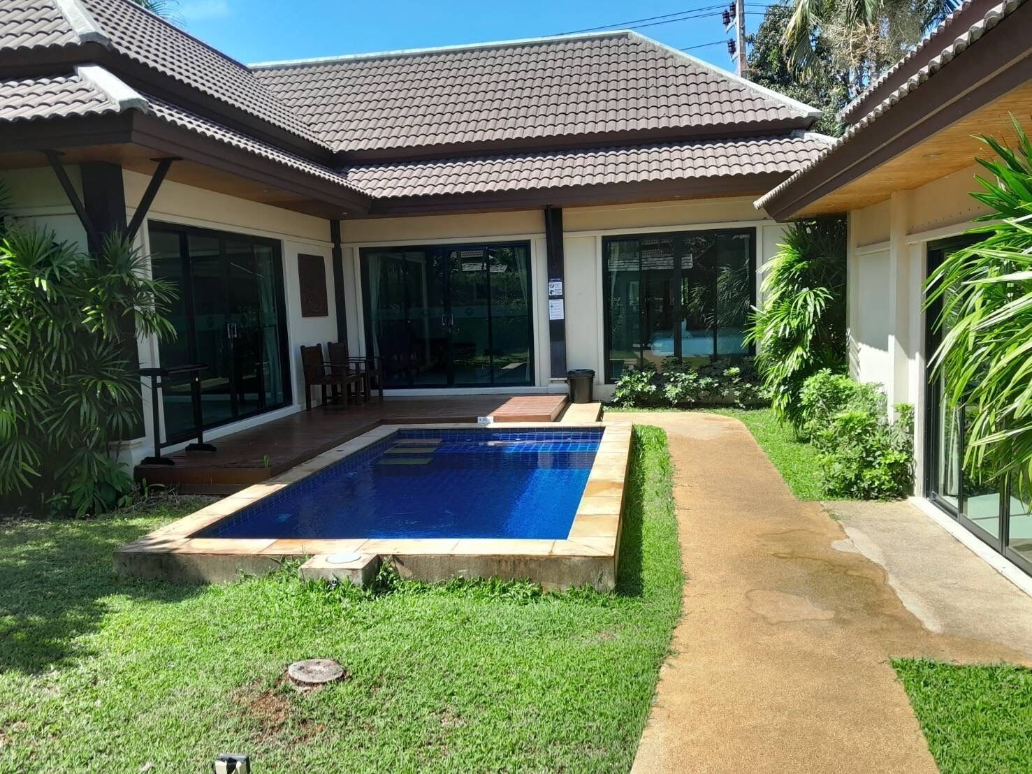 Une maison moderne dotée d’une piscine, d’une terrasse avec des chaises et d’un jardin bien entretenu.