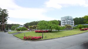 A modern building with a unique architectural design, surrounded by well-maintained lawns and trees.