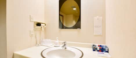 A hotel bathroom with a sink, mirror, and toiletries.