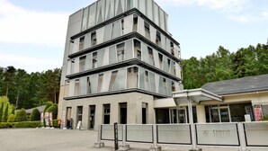 A modern multi-story building with a unique angular design, featuring large windows and a flat roof.