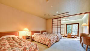A hotel room with two beds, a sitting area with a view, and traditional Japanese sliding doors.