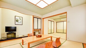 A traditional Japanese room with tatami flooring, a low table, and a television.
