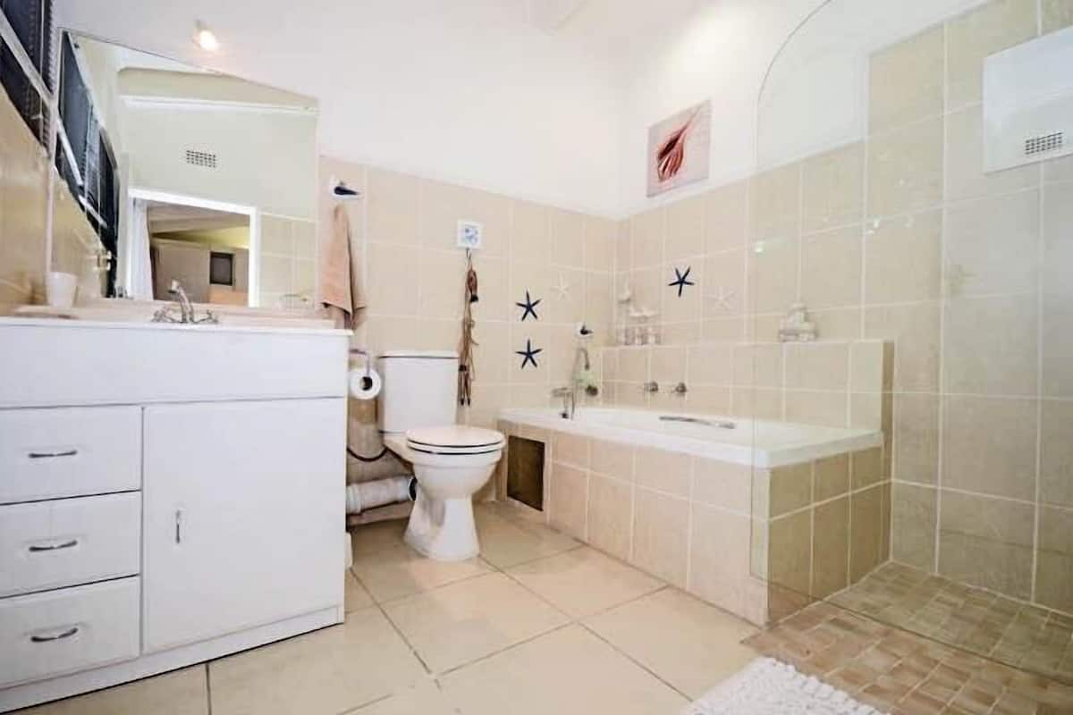Un baño con inodoro, lavamanos y zona de ducha.