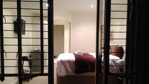 A hotel room with a bed, a chair, and a small table. - Noraclox Riverclub (Sandton)