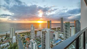 A cityscape with high-rise buildings, a waterfront, and a sunset.