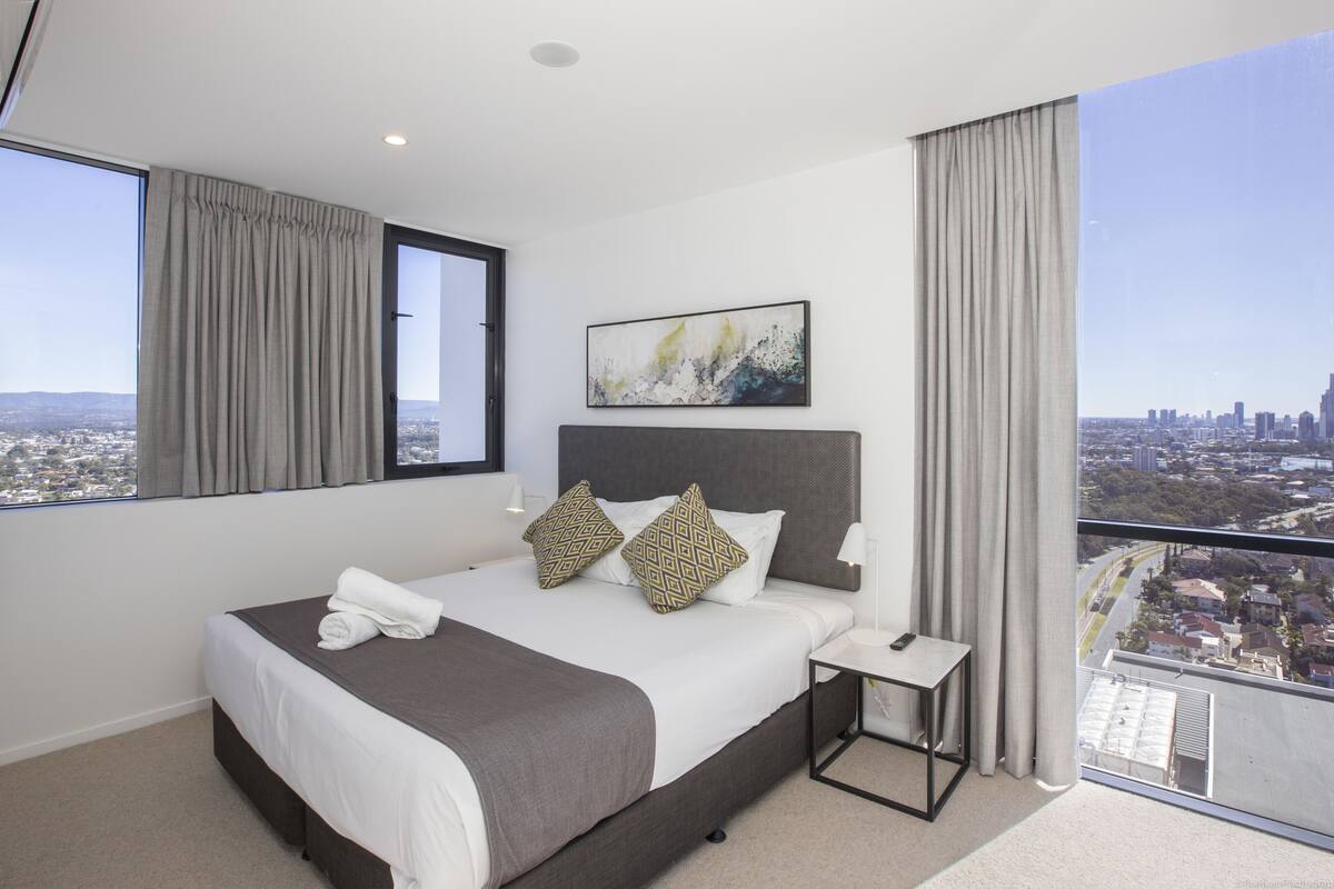Ein modernes Hotelzimmer mit einem großen Bett, einem Nachttisch und Blick auf die Stadt.