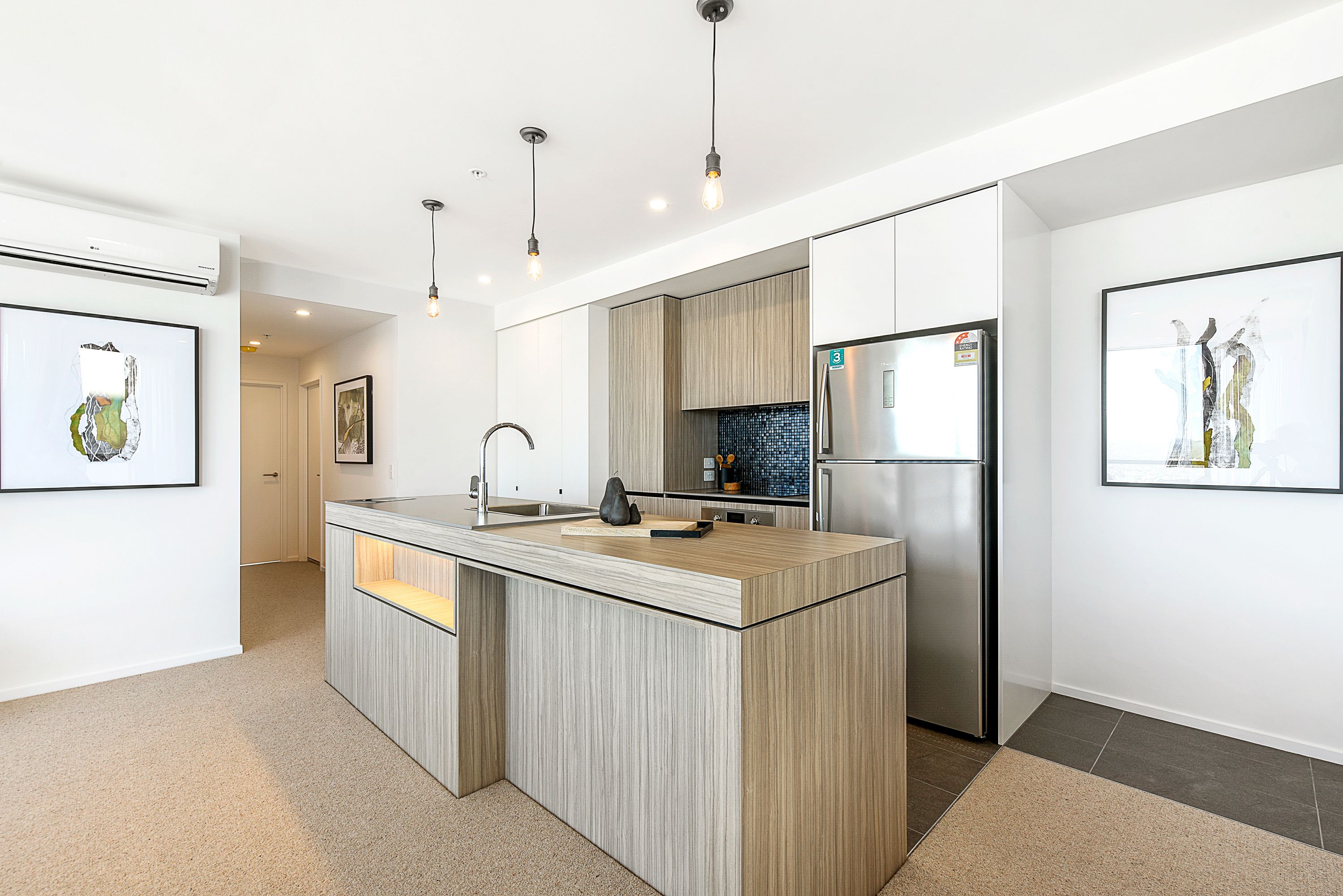 A modern kitchen with a central island, stainless steel appliances, and pendant lighting.