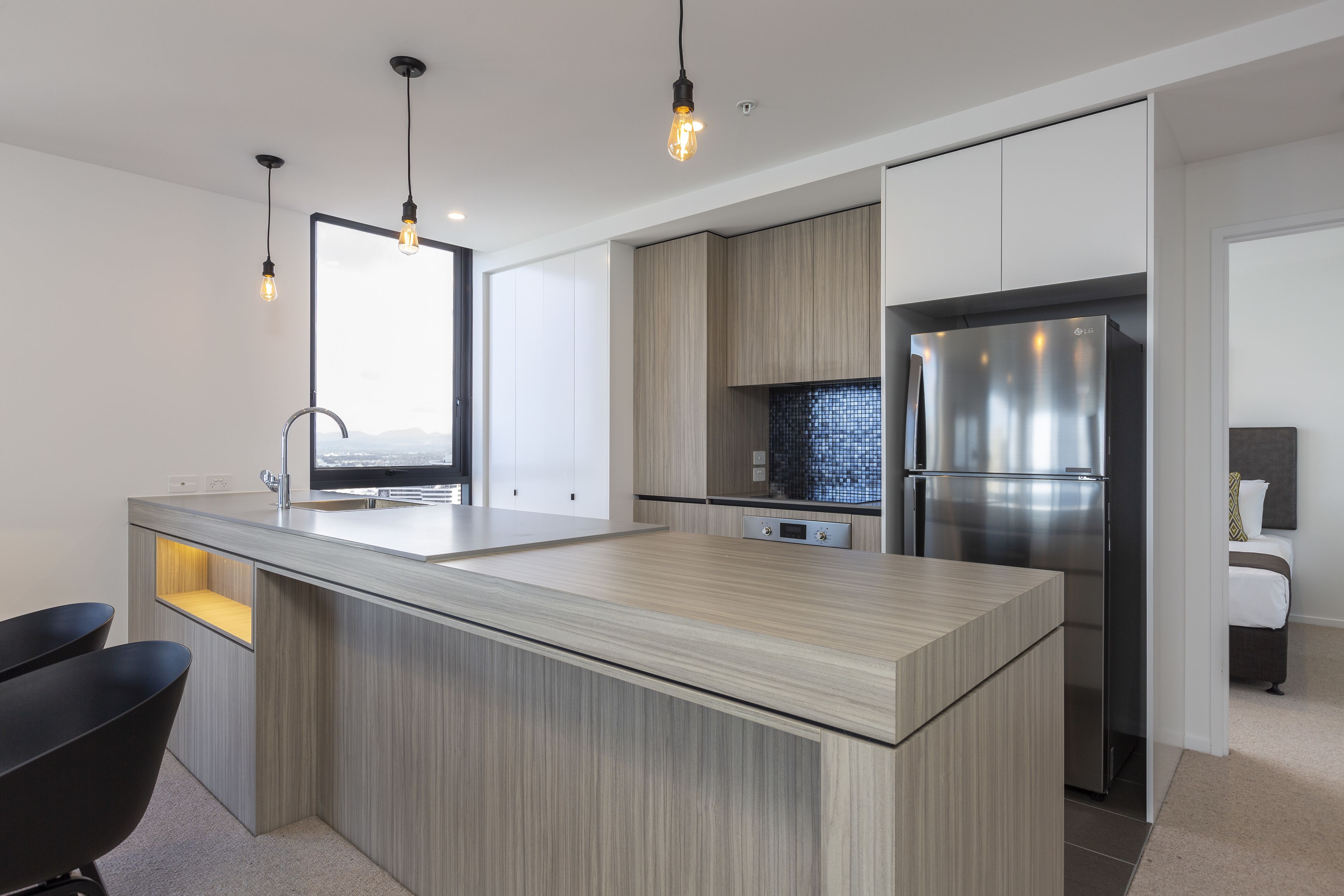 A modern kitchen with a central island, stainless steel appliances, and pendant lighting.