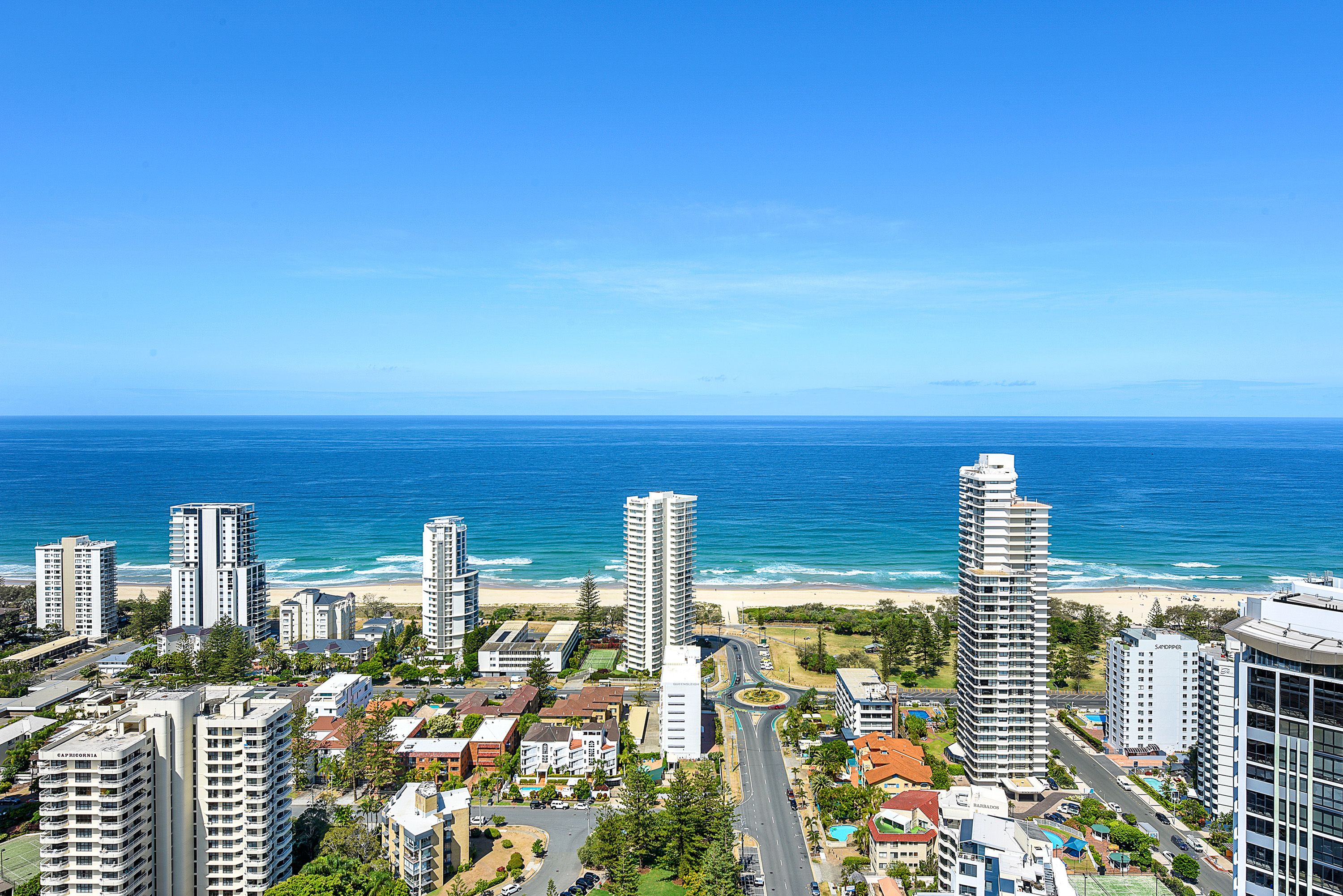 Un paysage urbain côtier avec de hauts immeubles, une plage et un ciel bleu dégagé.