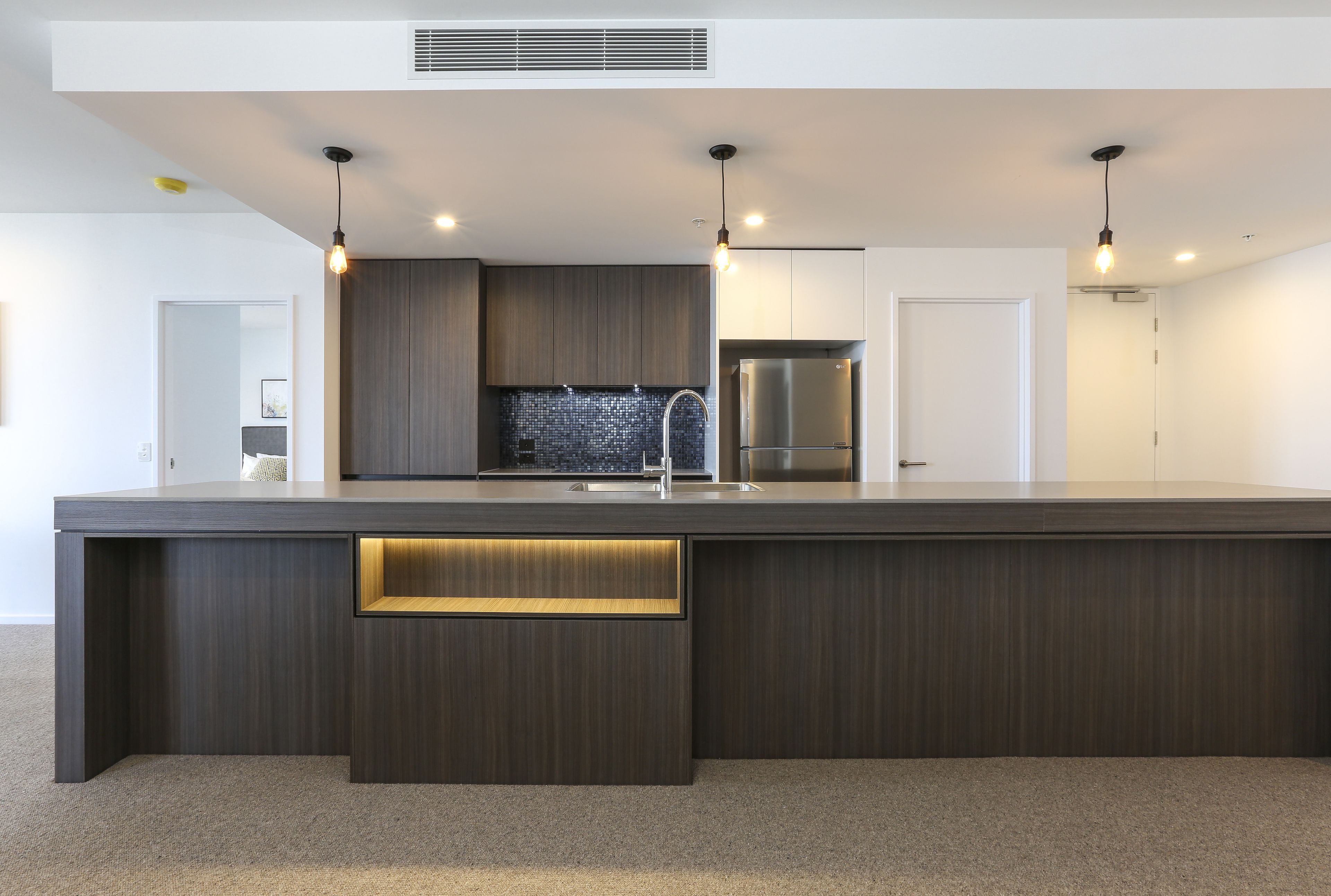 A modern kitchen with a central island, built-in appliances, and pendant lighting.