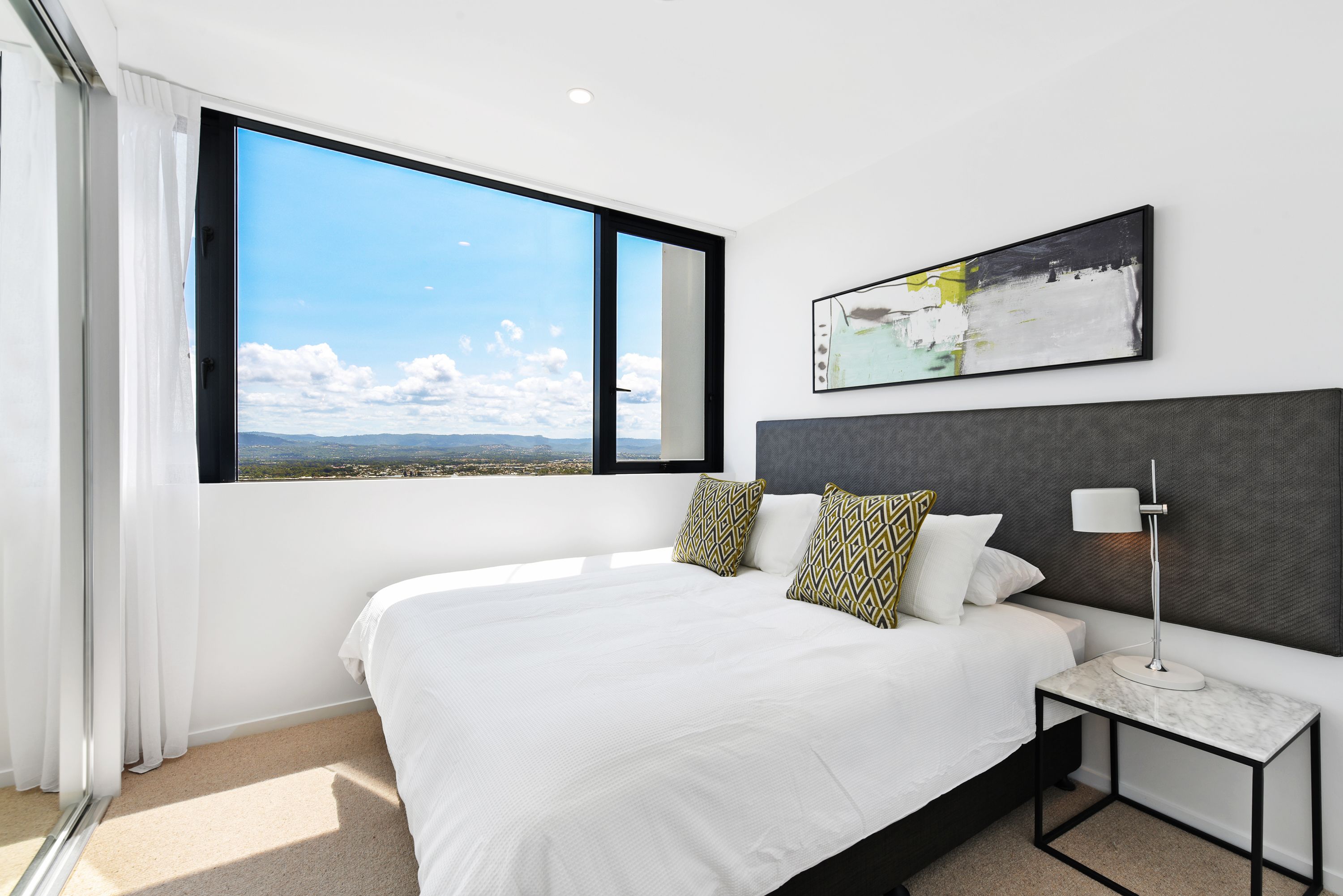 Een moderne hotelkamer met een groot bed, een nachtkastje, een vloerlamp en een schilderij aan de muur.