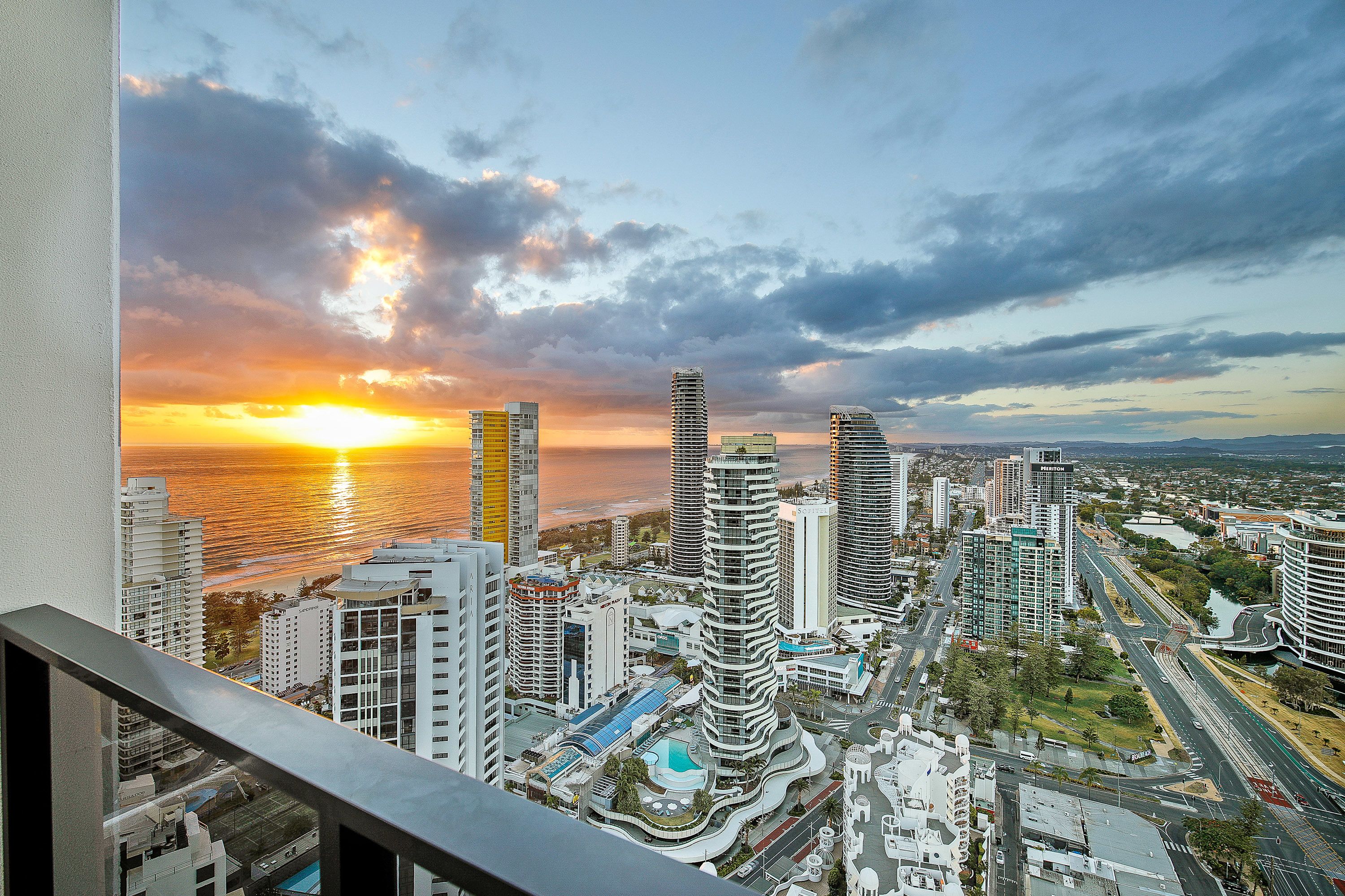 A cityscape with modern high-rise buildings, a waterfront, and a clear sky.