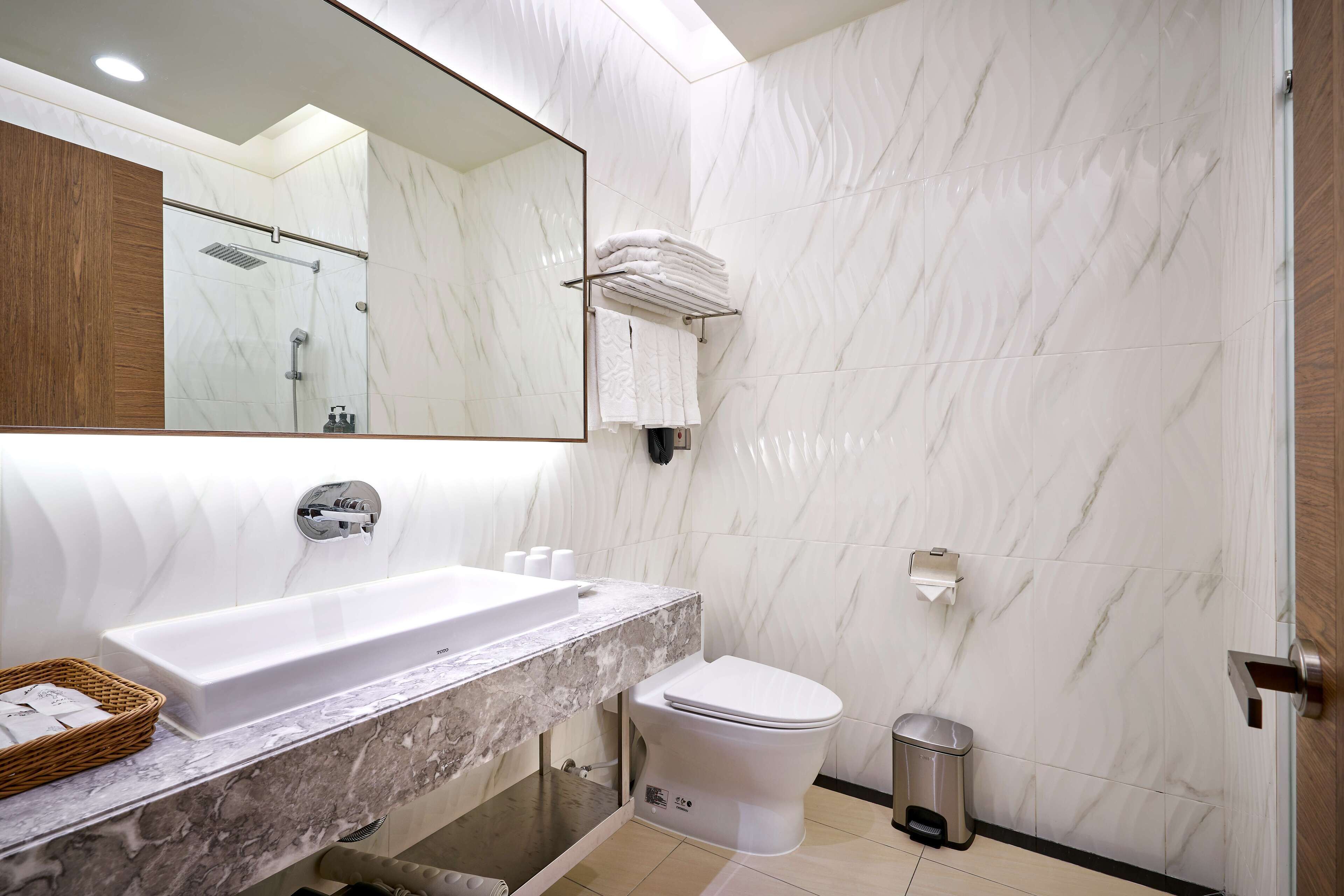 Un baño moderno con lavamanos de mármol, inodoro y zona de ducha.