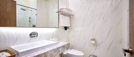 Un baño moderno con lavamanos de mármol, inodoro y zona de ducha.