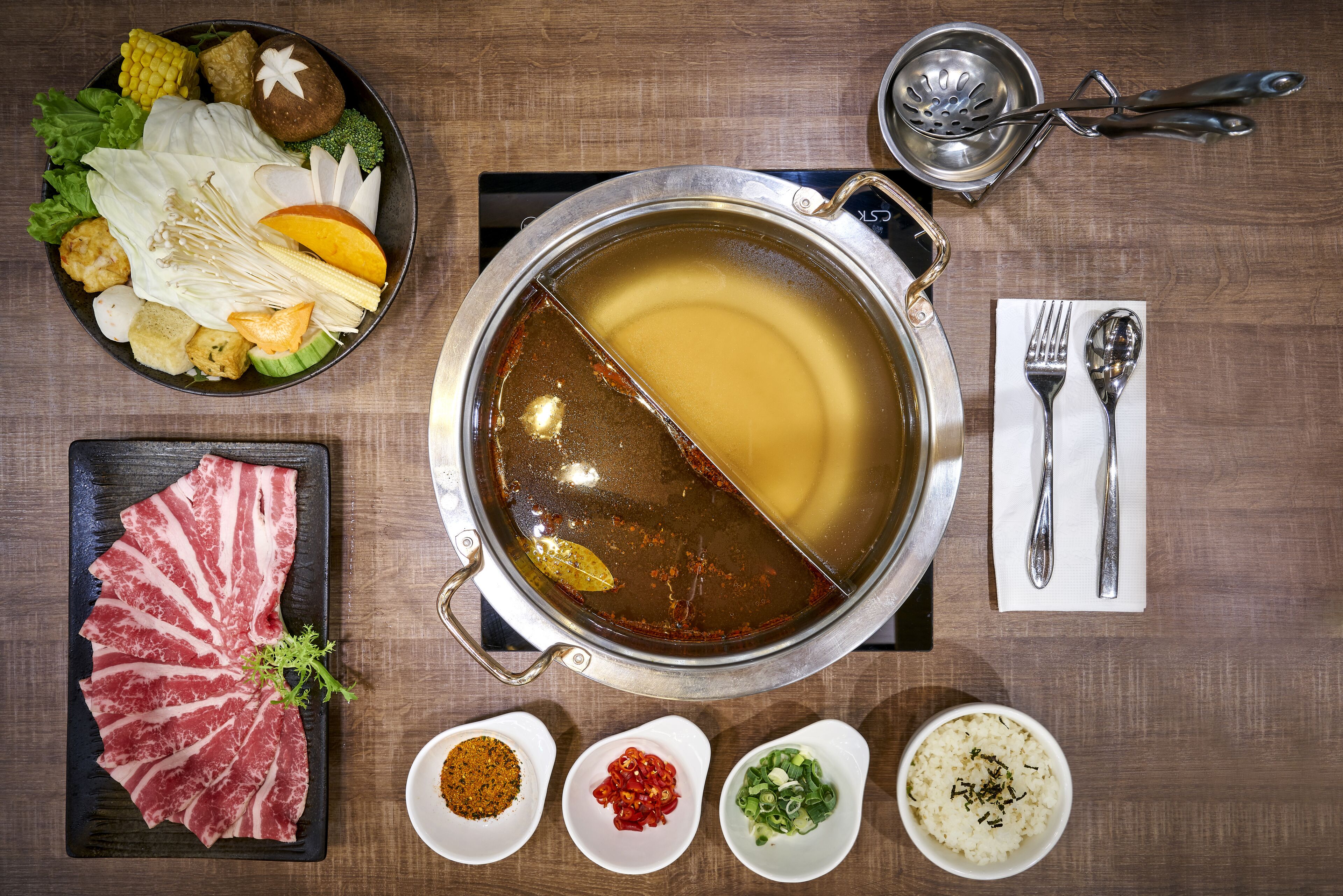 Una olla caliente con diversos ingredientes y salsas.