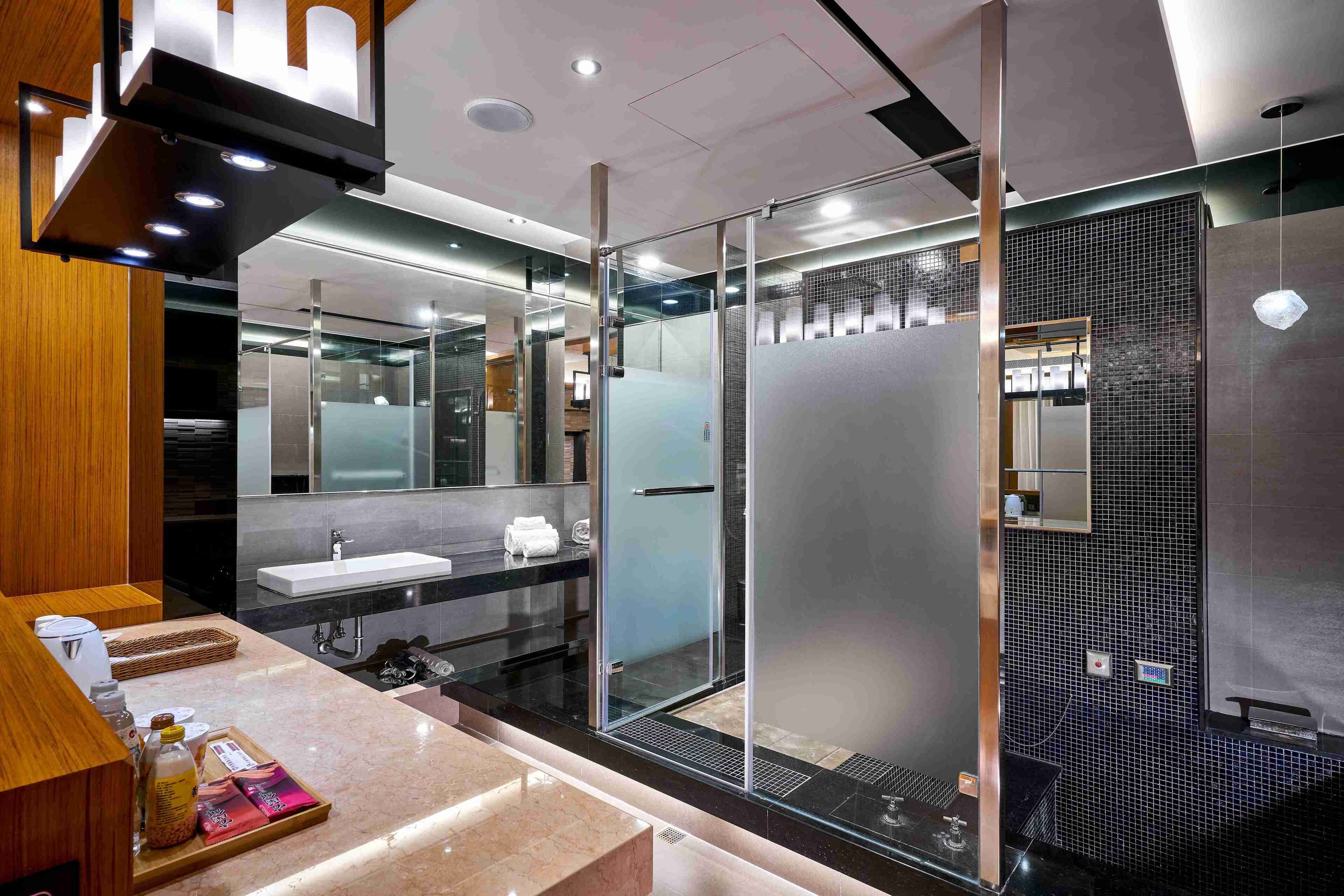 A modern bathroom with a glass shower enclosure, a sink, and a vanity with a tray of toiletries.