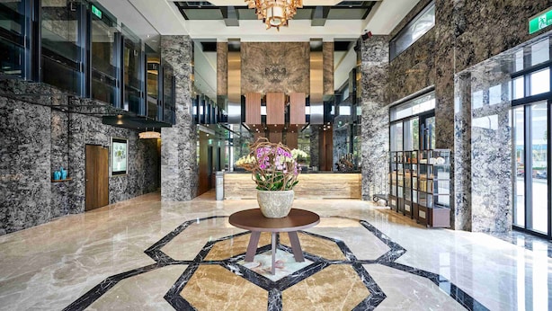 A spacious lobby with a marble floor, a central round table with a vase of flowers, and a chandelier. - So Fun Hotel (Wujie)
