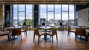 A spacious dining area with large windows offering a city view. - So Fun Hotel (Wujie)