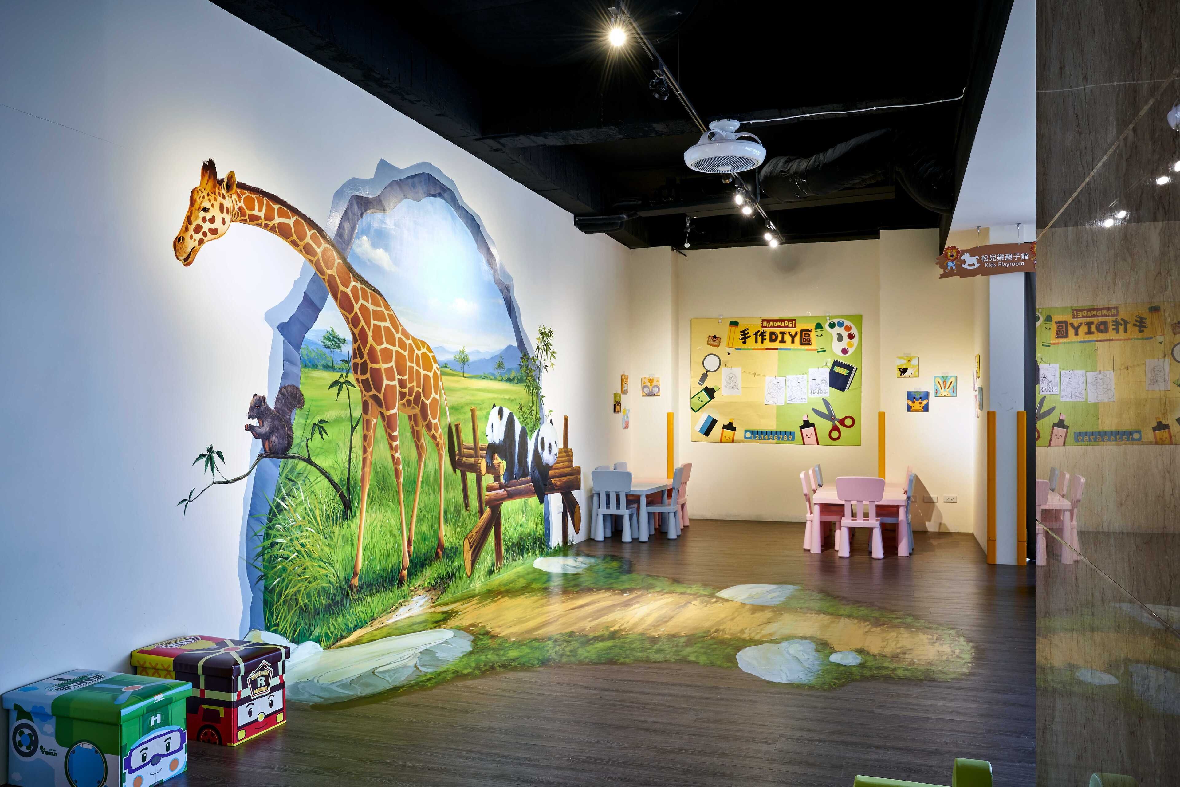 A children's playroom with a mural of a giraffe, panda, and squirrel, wooden flooring, and pink chairs.