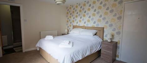 A bedroom with a bed, bedside table, and a wardrobe.
