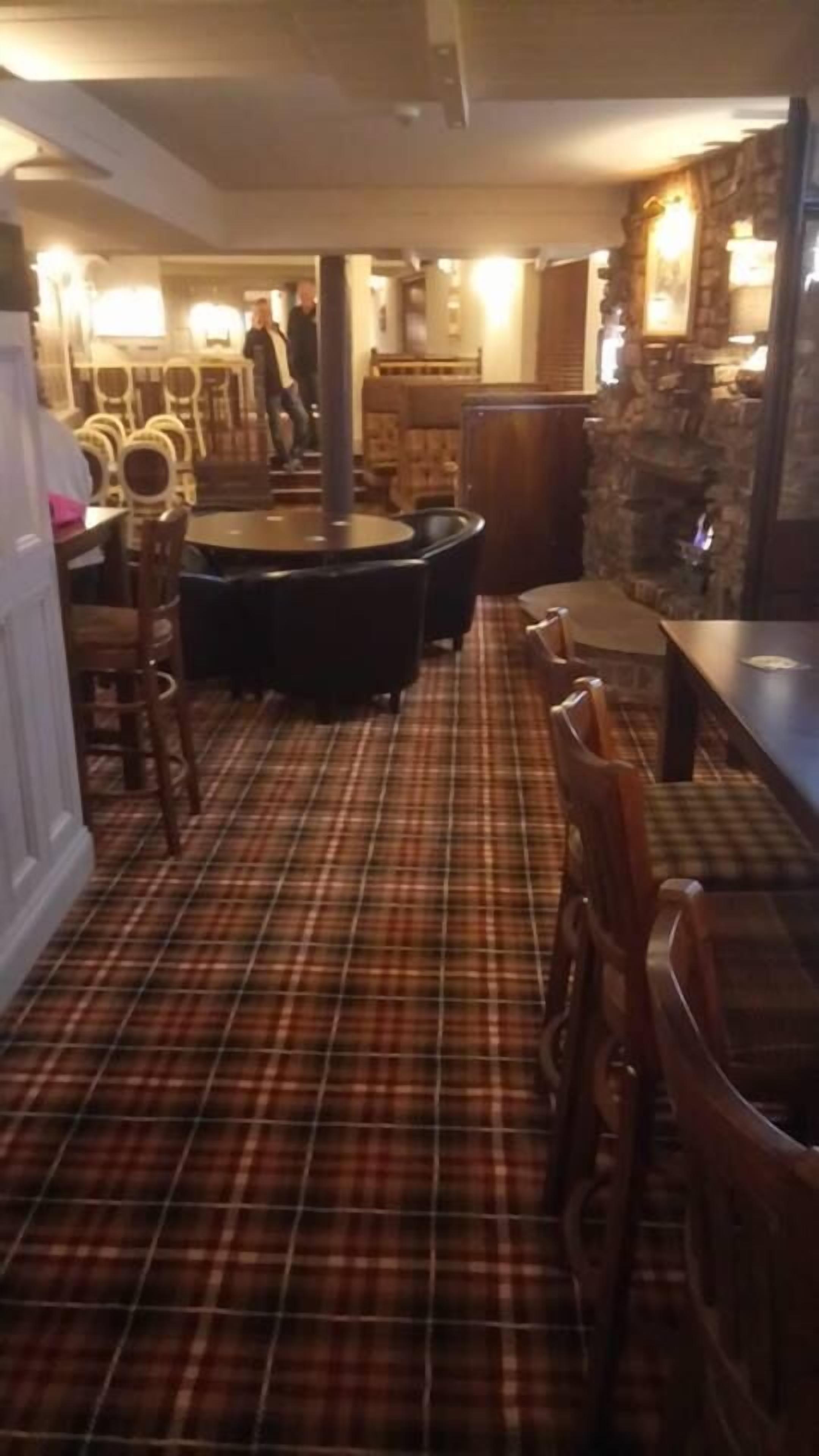 Un restaurante con suelo a cuadros, sillas y mesas de madera.