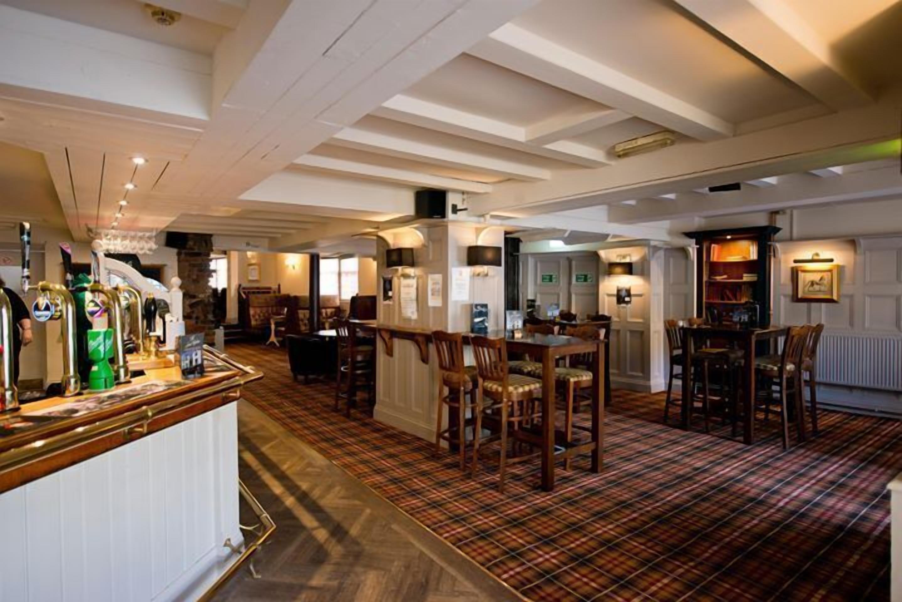 A hotel lobby with a bar area, wooden furniture, and a plaid carpet.