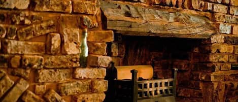 Una chimenea de piedra con una cepa de leña y una rejilla metálica.