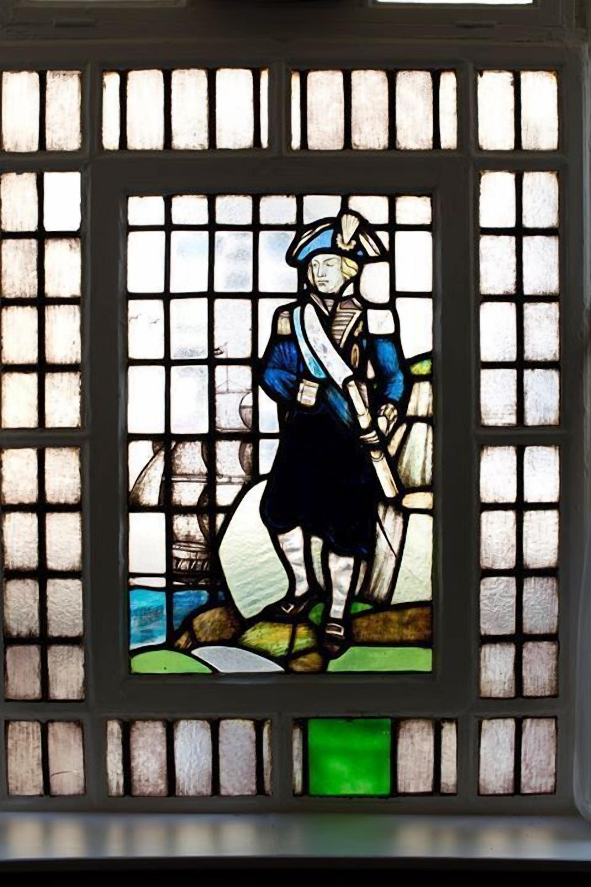 Una ventana de vitral con una figura vestida con ropas de época.