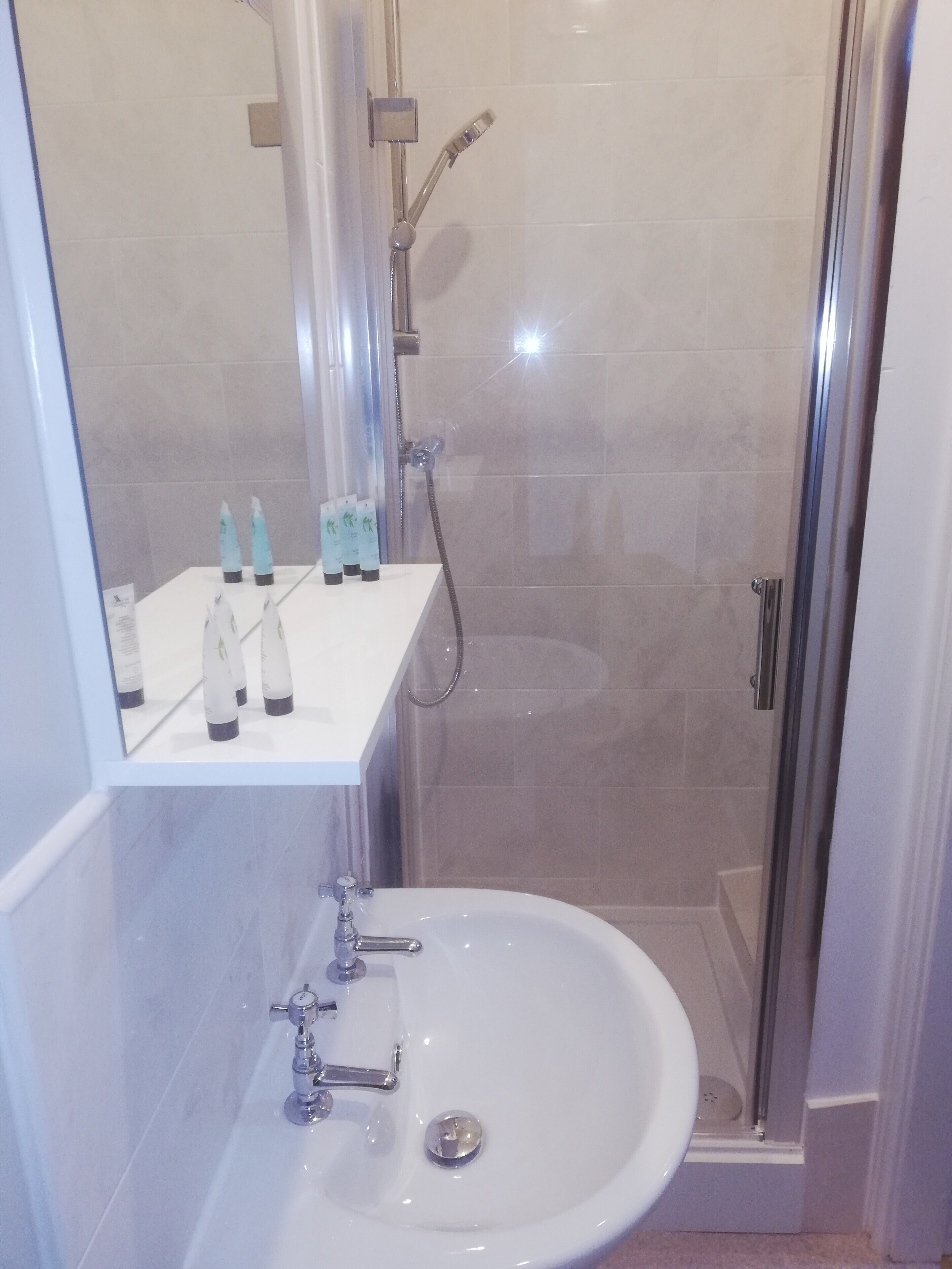 A modern bathroom with a glass shower enclosure, a white sink, and a mirror above the sink.