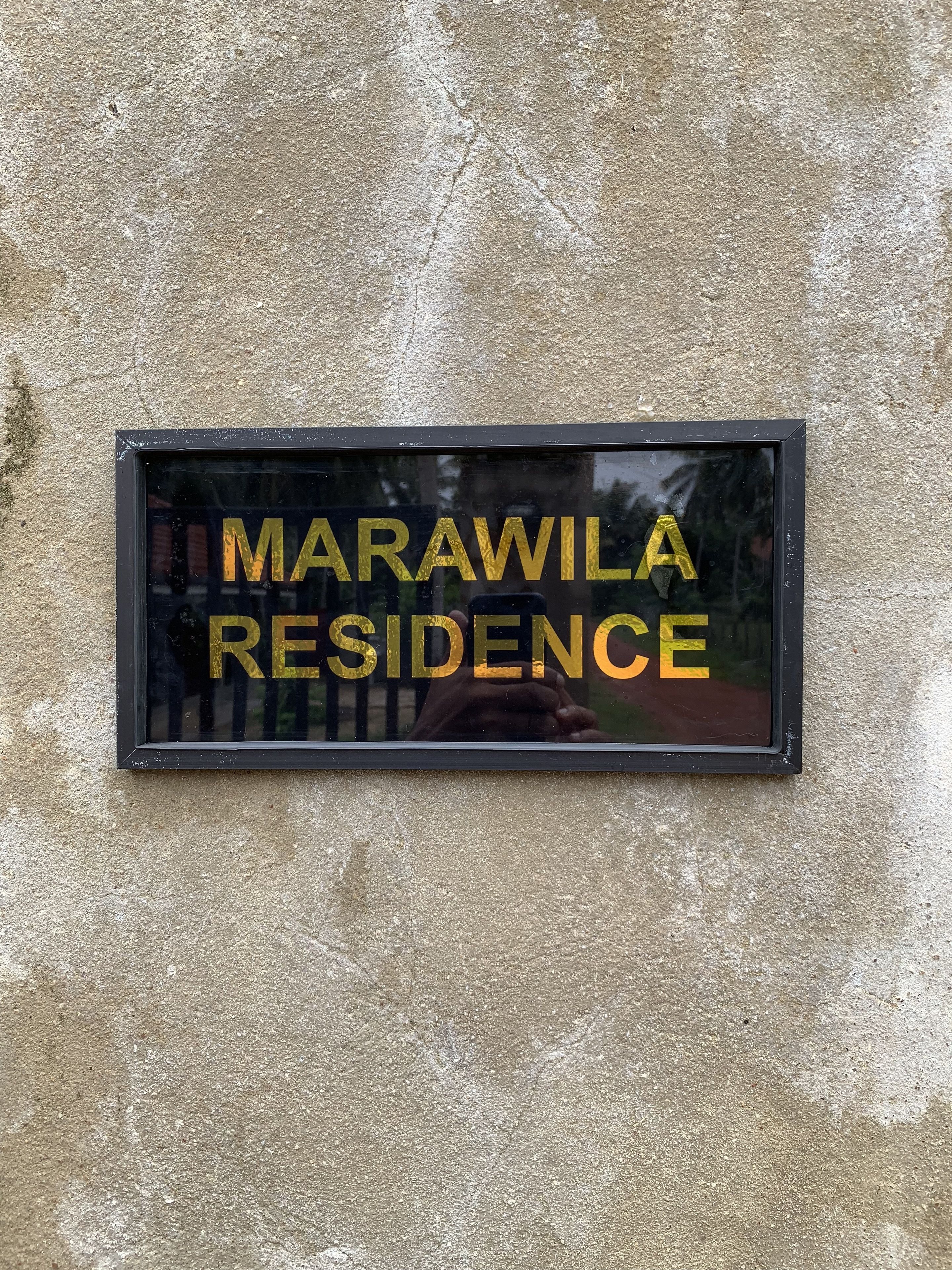 A sign with the text "MARAWILA RESIDENCE" on a textured wall.