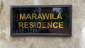 A sign with the text "MARAWILA RESIDENCE" on a textured wall.