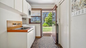 A narrow kitchen with a built-in oven, a sink, and a window overlooking a garden. - Rosella Retreat | Perfect getaway for family and friends (Blackheath)