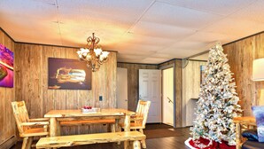 A rustic dining area with a wooden table and benches, a chandelier, and a decorated Christmas tree. - North Pole Christmas, Michigan Spectacular Lake Superior, Grand Island View! (Christmas)