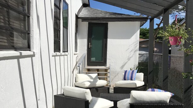 Een terras met rieten meubilair en een klein wit gebouw.