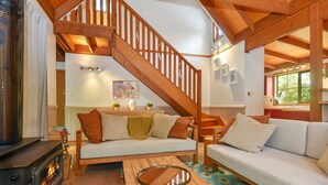 Una sala de estar acogedora con una escalera de madera, una chimenea y un sofá con cojines.