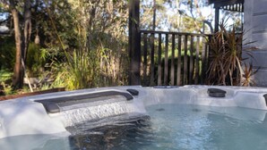 Un jacuzzi con cubierta de madera y vegetación circundante.