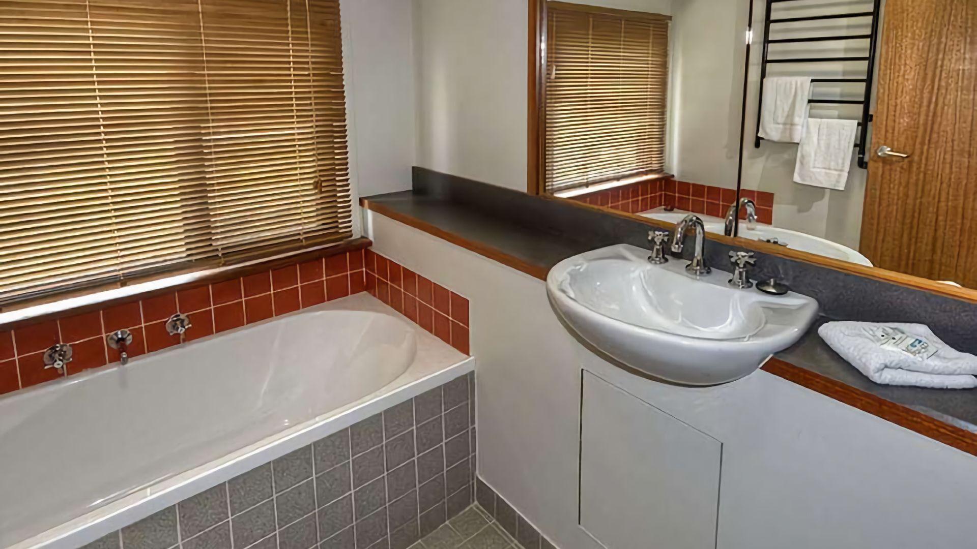 A bathroom with a bathtub, a sink, and a mirror.