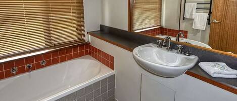 A bathroom with a bathtub, a sink, and a mirror.