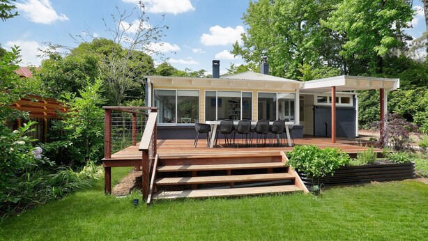 Et moderne hus med en terrasse, udendørs møbler og en have.