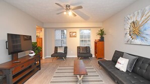 A living room with a TV, two sofas, a coffee table, and a ceiling fan. - Kings Manor · The Best of North Cincinnati @ Kings Manor (Kings Mills)