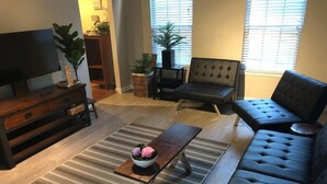 A living room with a sofa, a coffee table, a TV, and a striped rug. - Kings Manor · The Best of North Cincinnati @ Kings Manor (Kings Mills)