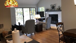 A living room with a fireplace, two patterned chairs, a television, and a ceiling fan. - Keowee Key Townhome - Pet Friendly, View of Golf Course plus Amenities (Salem)