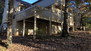 A two-story building with a balcony on the upper floor, surrounded by trees and covered in fallen leaves. - Keowee Key Townhome - Pet Friendly, View of Golf Course plus Amenities (Salem)