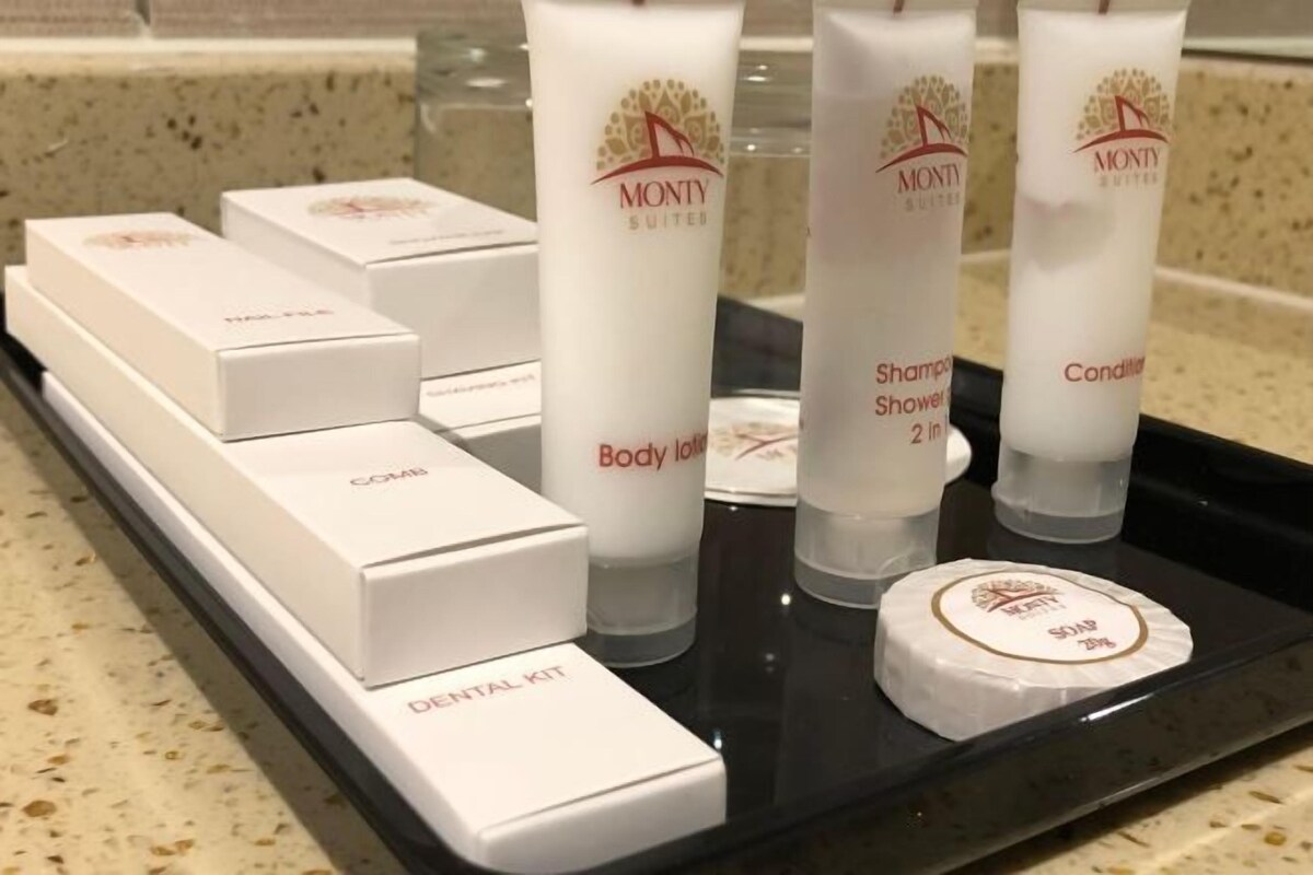 Un plateau contenant les produits de toilette de la gamme Monty Suites, notamment une lotion pour le corps, un gel douche, un après-shampoing et une trousse de soins dentaires.
