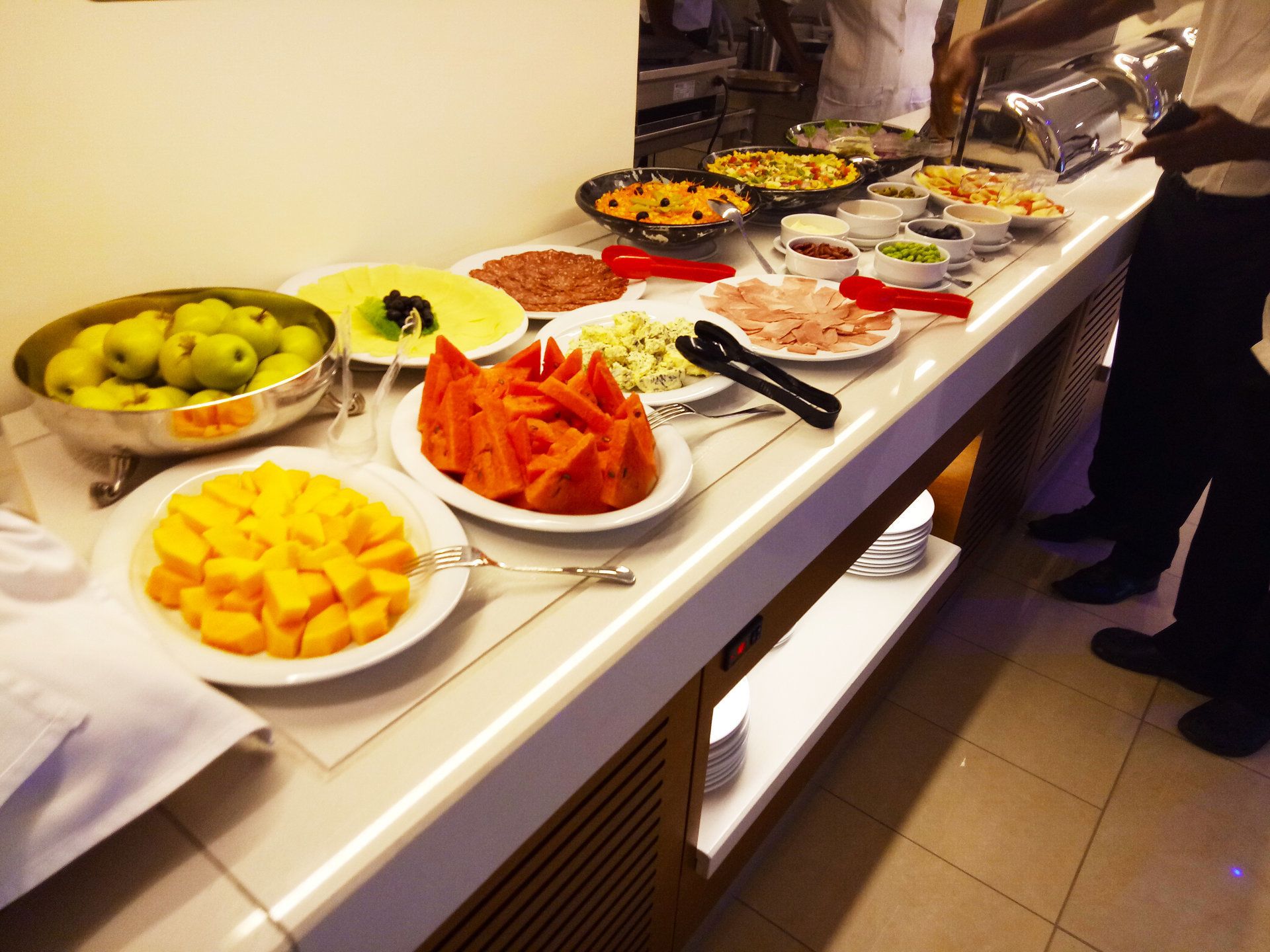 Un bufé con diversos platos, incluyendo frutas, verduras y carnes.
