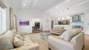 A modern living room with a sofa set, a coffee table, and a TV mounted on the wall.